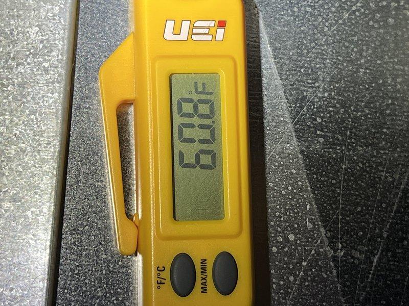 Responded to no cooling complaint on 12-year-old Goodman AC system that ran continuously overnight without providing adequate cooling. Upon arrival, performed diagnostic testing using digital thermometer and clamp meter to assess system performance and electrical parameters. Measured temperature readings at evaporator coil showing 90.6°F, indicating insufficient heat transfer. Tested electrical components including amperage draw and voltage levels to identify potential compressor or refrigerant issues. System was shut down by customer prior to arrival due to continuous runtime without cooling output. Documented findings with diagnostic measurements and photos for service records.