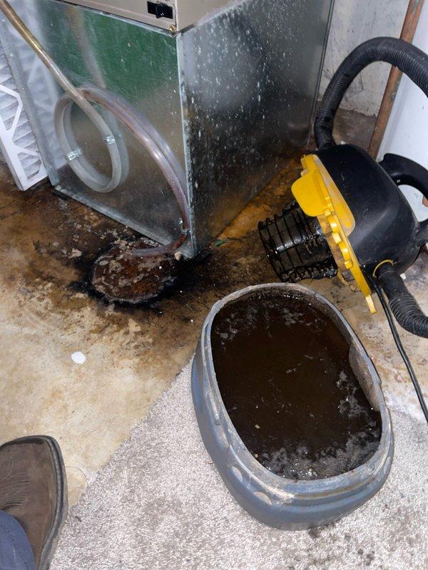 Responded to service call for basement A/C unit with water leaking onto floor instead of draining properly. Upon inspection, found clogged condensate drain line preventing proper drainage. Cleared blockage from drain line using wet/dry vacuum extraction method, removing accumulated debris and contaminated water from drain pan and line. Verified proper drainage flow restored, cleaned condensate pan, and inspected ductwork and air handler for moisture damage and proper operation. Unit returned to normal function with condensate now draining correctly through drain line.