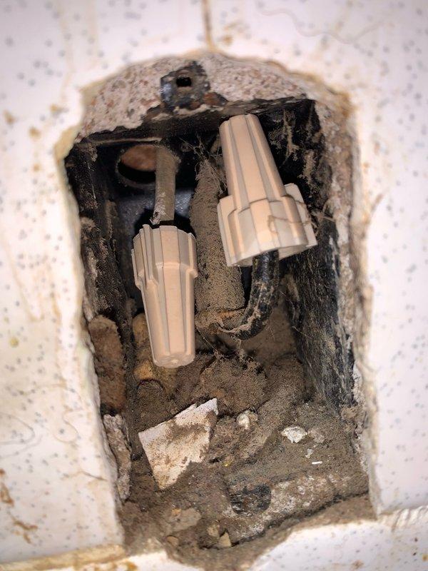 Responded to report of exposed wiring in kitchen area. Upon inspection, discovered open electrical junction box recessed in wall with active wire connections exposed through damaged tile and drywall. Identified two wire connectors (wire nuts) joining circuit conductors within box showing signs of age and accumulated debris. Verified wire connections were secure and properly terminated, confirmed no exposed bare conductors were making contact, and ensured all splices were contained within approved junction box with adequate wire fill capacity. Electrical hazard was mitigated by securing connections and providing recommendations for proper cover plate installation to enclose junction box per code requirements.