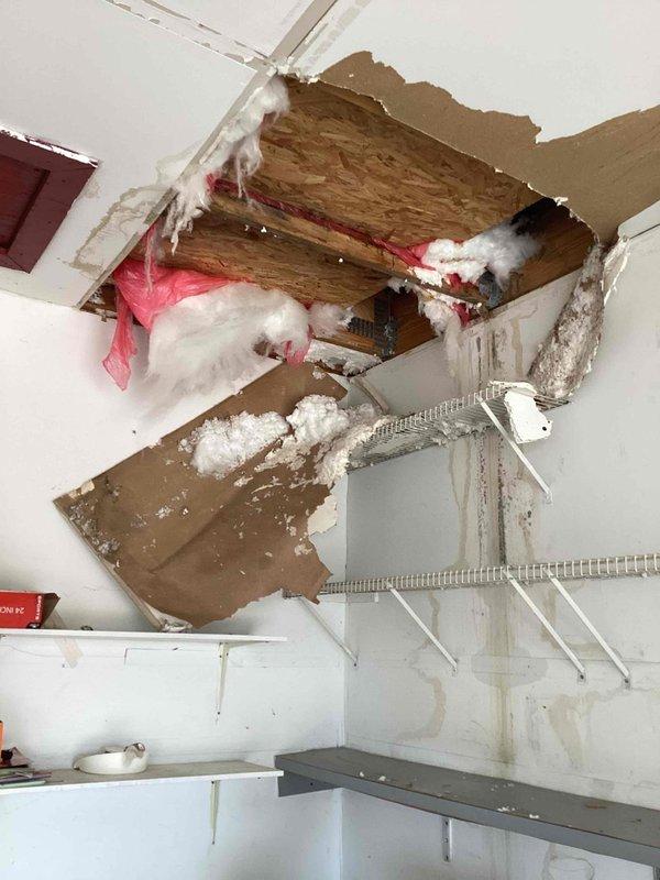 Responded to service call for reported water leak initially suspected to be plumbing-related. Upon investigation, determined the actual source was the attic air handler unit leaking condensate, which caused significant ceiling damage with water infiltration through drywall. Documented extensive structural damage including compromised ceiling material, exposed framing, and displaced insulation. Identified air handler condensate drain system as the source of the leak. Photographed the PVC drain trap assembly and surrounding areas showing evidence of water damage to wooden structural components. Recommended diagnostic evaluation and repair of the air handler condensate drainage system to prevent further water damage.