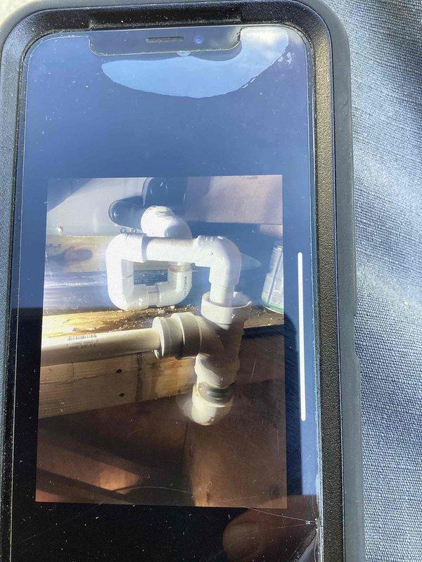 Responded to service call for reported water leak initially suspected to be plumbing-related. Upon investigation, determined the actual source was the attic air handler unit leaking condensate, which caused significant ceiling damage with water infiltration through drywall. Documented extensive structural damage including compromised ceiling material, exposed framing, and displaced insulation. Identified air handler condensate drain system as the source of the leak. Photographed the PVC drain trap assembly and surrounding areas showing evidence of water damage to wooden structural components. Recommended diagnostic evaluation and repair of the air handler condensate drainage system to prevent further water damage.