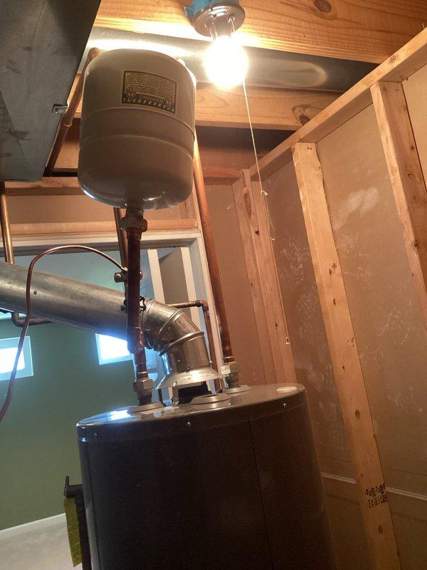 Responded to service call for potential leak at expansion tank connection line on 40-gallon gas water heater in basement. Inspected expansion tank mounting, connection fittings, and associated piping for signs of moisture or corrosion. Examined anode rod condition to assess tank longevity and internal corrosion protection. Verified all connections at water heater top, including pressure relief valve, copper fittings, and metallic flex connectors were properly secured. Documented existing installation with photographs showing water heater, expansion tank, piping configuration, and surrounding water treatment system components including filtration units and softener tanks.