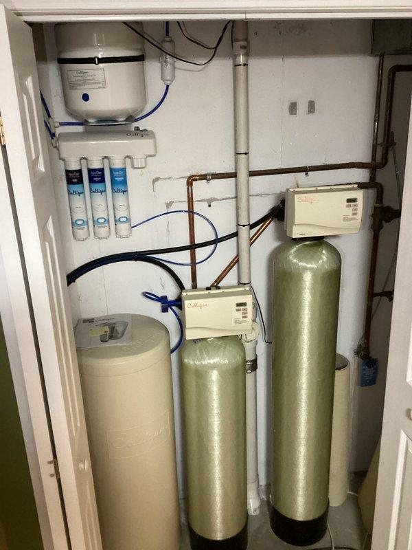 Responded to service call for potential leak at expansion tank connection line on 40-gallon gas water heater in basement. Inspected expansion tank mounting, connection fittings, and associated piping for signs of moisture or corrosion. Examined anode rod condition to assess tank longevity and internal corrosion protection. Verified all connections at water heater top, including pressure relief valve, copper fittings, and metallic flex connectors were properly secured. Documented existing installation with photographs showing water heater, expansion tank, piping configuration, and surrounding water treatment system components including filtration units and softener tanks.