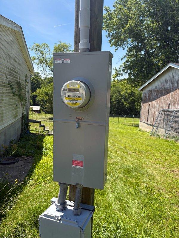Responded to service call for non-functional outlet and fan in living room. Upon arrival, traced electrical circuit from affected fixtures to exterior meter installation. Inspected main electrical service panel and meter assembly mounted on utility pole, verifying proper meter operation and secure conduit connections. Documented exterior electrical infrastructure including meter enclosure, disconnect box, and PVC conduit routing for service records.