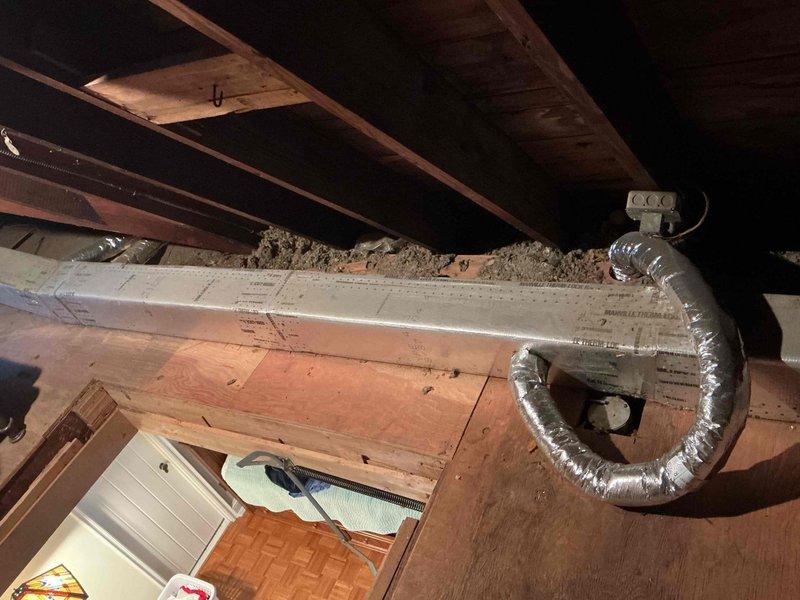 Responded to no cooling call on second floor Unico system. Upon arrival, learned unit had been frozen the previous day and was turned off. Accessed attic space via pull-down stairs to inspect system. Found evaporator coil with visible copper tubing and heat exchanger assembly. Coil showed signs of oxidation and discoloration on copper lines, with brass valve and fittings present. Inspected flexible aluminum ductwork routed through attic joists and spray foam insulation areas. System had been shut down allowing coil to thaw. Documented equipment condition with photos showing coil assembly and attic installation layout for service records.