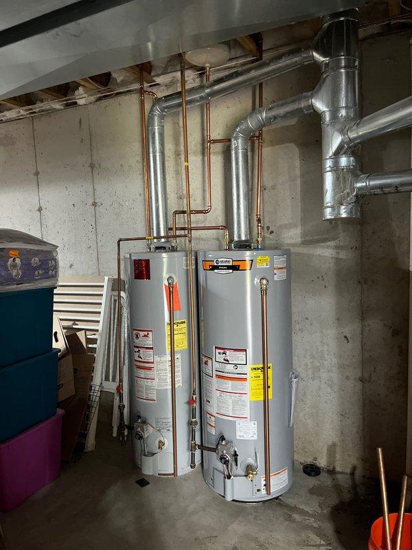 Completed installation of two 50-gallon gas water heaters in basement utility area with new copper supply piping and metallic exhaust venting. Reconfigured copper connections to accommodate dual-unit setup, running vertical supply lines along concrete wall and horizontal vent ducting with proper elbow joints to ceiling exhaust. All units secured, labeled, and tested for proper operation with adequate clearance maintained per manufacturer specifications.