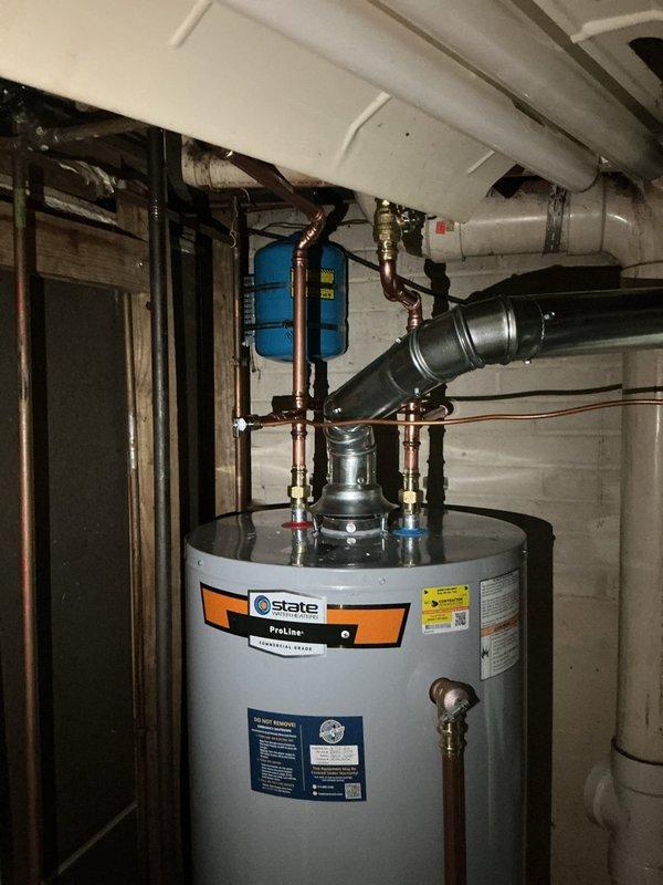 Responded to no hot water complaint in basement. Removed and replaced existing failed water heater with new 50-gallon gas tall unit. Installed all required plumbing connections including hot and cold water lines with brass shut-off valves, pressure relief valve with proper discharge piping, and gas line connections. Mounted thermal expansion tank to wall with secure strapping. Connected exhaust venting system to ensure proper combustion air flow and safety compliance. Applied plumbing identification sticker and verified all connections for leaks. Tested unit operation and confirmed proper ignition, heating function, and temperature settings. System restored to full operational status with adequate hot water supply.