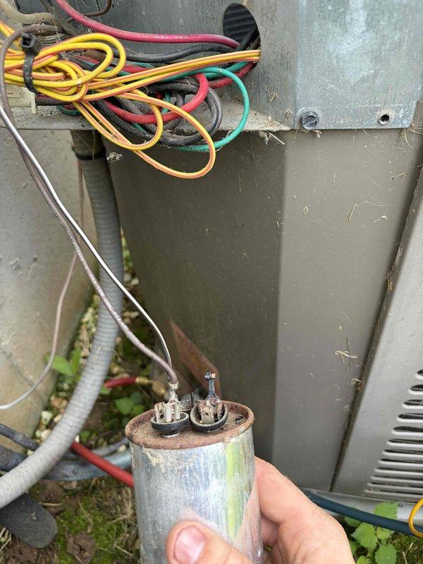 Responded to no cooling call on 10+ year old outdoor unit located on side of home. Upon inspection, found severely corroded dual-run capacitor with visible rust, oxidation, and deteriorated terminals affecting system operation. Diagnosed failed capacitor as cause of no cooling condition. Removed and replaced defective capacitor with new component. Tested system operation and verified proper cooling function restored. Unit operating within normal parameters at time of departure.