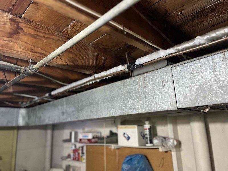Responded to no cooling complaint on residential air conditioning system less than 10 years old. Upon arrival, found evaporator coil completely frozen with heavy ice buildup on refrigerant lines and coil surfaces. Advised customer to shut off unit and run fan only to allow ice to thaw. Identified severe frost accumulation on copper refrigerant lines and evaporator coil assembly indicating restricted airflow or possible low refrigerant charge. System requires follow-up diagnostic once ice has melted to determine root cause, which may include dirty air filter, blocked return air, failed blower motor, low refrigerant due to leak, or malfunctioning metering device.