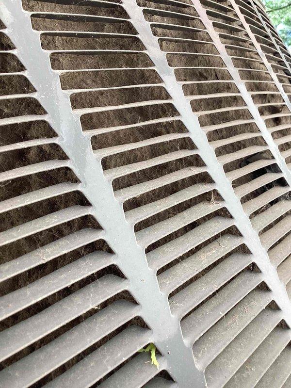 Responded to no-cooling complaint on single outdoor condensing unit. Upon arrival, found extensive dirt, dust, and debris accumulation throughout the exterior grille louvers and internal coil assembly, severely restricting airflow and heat transfer capability. The evaporator coil fins were completely clogged with tan-colored contamination, and copper refrigerant lines showed heavy dust coating. Customer had been advised to shut system off due to excessive condensation on indoor unit, which was consistent with reduced airflow causing coil icing. Documented existing conditions with photographs showing the extent of contamination on both exterior vents and internal components, confirming the unit required professional cleaning to restore proper operation and resolve the no-cooling condition.