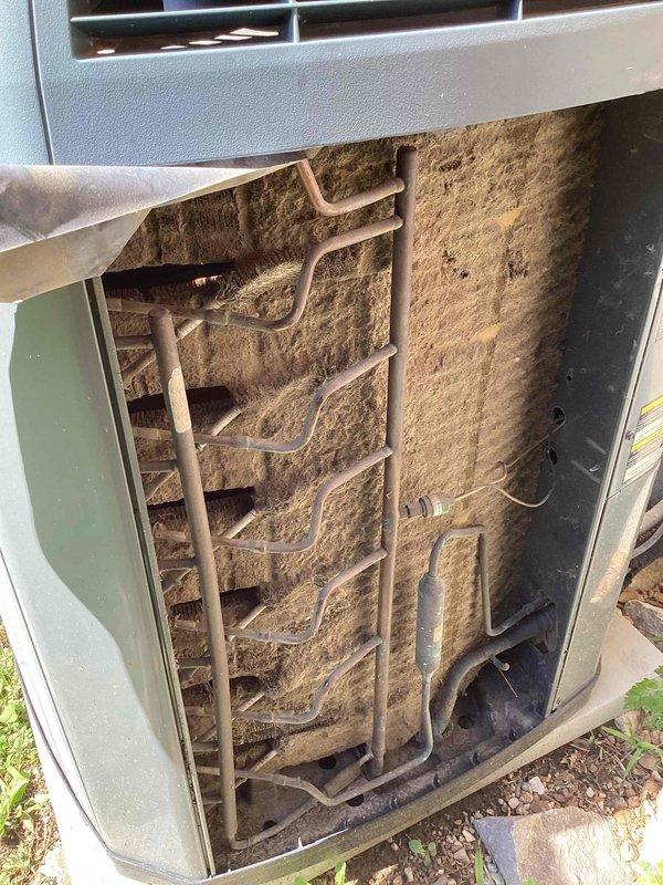 Responded to no-cooling complaint on single outdoor condensing unit. Upon arrival, found extensive dirt, dust, and debris accumulation throughout the exterior grille louvers and internal coil assembly, severely restricting airflow and heat transfer capability. The evaporator coil fins were completely clogged with tan-colored contamination, and copper refrigerant lines showed heavy dust coating. Customer had been advised to shut system off due to excessive condensation on indoor unit, which was consistent with reduced airflow causing coil icing. Documented existing conditions with photographs showing the extent of contamination on both exterior vents and internal components, confirming the unit required professional cleaning to restore proper operation and resolve the no-cooling condition.