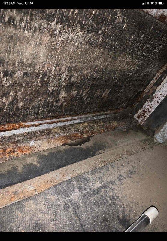 Responded to reported water leak from ductwork in basement and exterior condenser unit. Upon inspection, discovered significant water damage and mold growth on basement walls near HVAC system, with deteriorated surfaces and rust-stained baseboards indicating prolonged moisture intrusion. Investigated source of leak and found condensate drainage issue affecting both the basement ductwork and outdoor unit. Examined indoor air handler and found blower wheel heavily contaminated with dust and debris accumulation, which was restricting airflow and contributing to condensate backup. Cleaned blower assembly and addressed drainage concerns to resolve active leak. Additionally installed new thermostat as requested to restore proper system control functionality for the two-unit system.