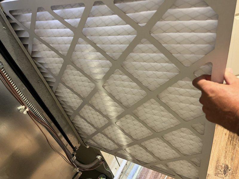 Responded to no cooling complaint on 10+ year old geothermal system located on second floor. Upon arrival, found return air filter heavily restricted with debris, causing reduced airflow and inadequate cooling performance. Measured supply air temperature at 64.9°F, confirming insufficient cooling output. Replaced dirty air filter with new pleated filter, restoring proper airflow to system. System operational and cooling properly upon departure.