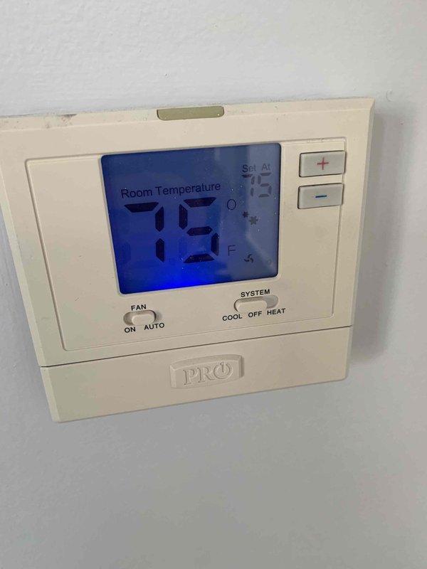 Responded to second opinion request for AC unit with reported 11-degree temperature differential on return air. Performed diagnostic evaluation on 10+ year old outdoor unit located at side of home. Measured and verified system temperatures using digital instrumentation at return air location in crawlspace area. Inspected thermostat operation showing 73°F room temperature setting with system controls in proper position. Documented findings with diagnostic measurements and system component photos for home sale inspection requirements.