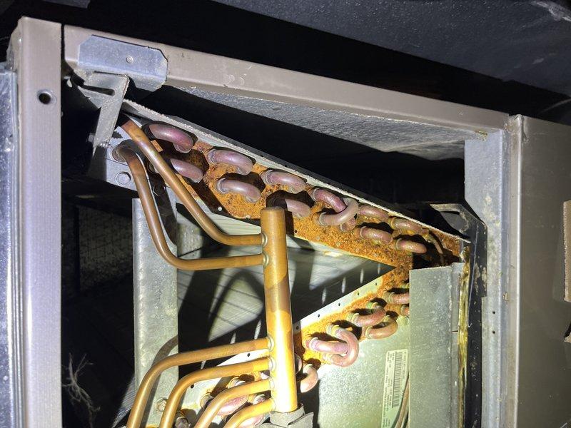 Responded to no-cooling complaint with unit running continuously and unable to maintain temperature below 81°F. Upon arrival, performed diagnostic assessment of 10-year-old air conditioning system. Inspected outdoor condenser unit and found operational compressor and fan motor. Accessed indoor air handler and discovered severely corroded evaporator coil with extensive rust and oxidation throughout the fin assembly. Copper refrigerant lines showed significant deterioration and corrosion. The degraded coil condition was restricting airflow and heat transfer capacity, preventing adequate cooling performance. Documented equipment condition with photographs showing the extent of corrosion damage to both the evaporator coil and refrigerant piping. Advised that the corroded evaporator coil has failed and requires replacement to restore proper system operation and cooling capacity.