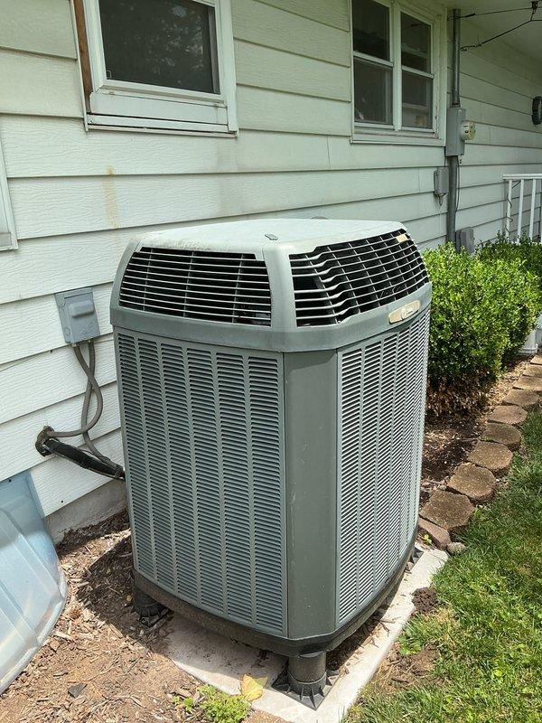 Responded to service call for 15-year-old air conditioning system experiencing intermittent outdoor fan operation, with condenser fan starting briefly then shutting off. Performed diagnostic inspection of outdoor condensing unit positioned on concrete pad against exterior wall. Documented equipment condition through photographic evidence showing unit installation, surrounding area, and overall system accessibility for future reference.