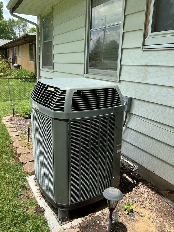 Responded to service call for 15-year-old air conditioning system experiencing intermittent outdoor fan operation, with condenser fan starting briefly then shutting off. Performed diagnostic inspection of outdoor condensing unit positioned on concrete pad against exterior wall. Documented equipment condition through photographic evidence showing unit installation, surrounding area, and overall system accessibility for future reference.