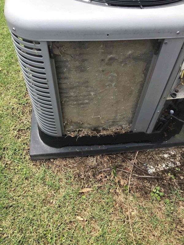Responded to no cooling complaint on 2017 residential air conditioning system located in side yard. Upon arrival, found outdoor condenser unit with severely restricted airflow due to heavy accumulation of dirt, dust, grass clippings, leaves, and organic debris completely blocking the external filter and intake area. The dense buildup was preventing proper air circulation through the condenser coil, resulting in significantly reduced cooling capacity and poor system performance. Removed and cleaned clogged filter, cleared all debris from unit housing and intake areas, and restored proper airflow to condenser. Verified system operation and confirmed adequate cooling performance restored to normal levels.