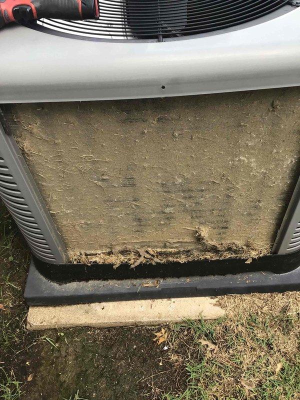 Responded to no cooling complaint on 2017 residential air conditioning system located in side yard. Upon arrival, found outdoor condenser unit with severely restricted airflow due to heavy accumulation of dirt, dust, grass clippings, leaves, and organic debris completely blocking the external filter and intake area. The dense buildup was preventing proper air circulation through the condenser coil, resulting in significantly reduced cooling capacity and poor system performance. Removed and cleaned clogged filter, cleared all debris from unit housing and intake areas, and restored proper airflow to condenser. Verified system operation and confirmed adequate cooling performance restored to normal levels.