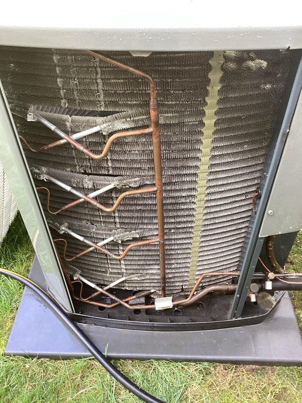 Responded to no cooling complaint on outdoor condensing unit located at rear of property. Upon arrival, connected manifold gauges to service ports and recorded system pressures and temperatures. R-410A refrigerant system showed abnormal operating pressures with high-side reading of 224 PSI and temperature differential indicating potential airflow restriction. Removed access panel and inspected condenser coil assembly, which revealed moderate accumulation of dirt and debris between aluminum fins. Condenser coil showed signs of reduced heat transfer efficiency due to contamination buildup. Copper refrigerant lines displayed normal age-related oxidation with no visible leaks detected. System components appeared structurally sound with no immediate mechanical failures observed. Documented equipment condition with diagnostic photos for service records.