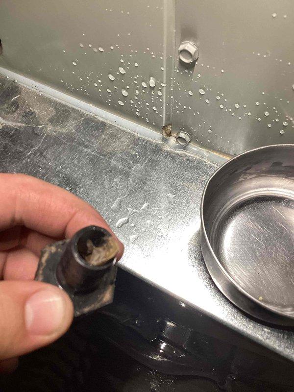 Responded to callback for water leakage issue around AC unit in basement. Upon arrival, found condensate drain line completely clogged, causing water to overflow from drain pan onto floor. Removed heavily corroded drain fitting that had deteriorated and was restricting water flow. Cleared blockage from condensate line, replaced damaged coupling, and tested system operation. Verified proper drainage with no leaks present. Unit cooling normally with condensate now draining properly through repaired line.