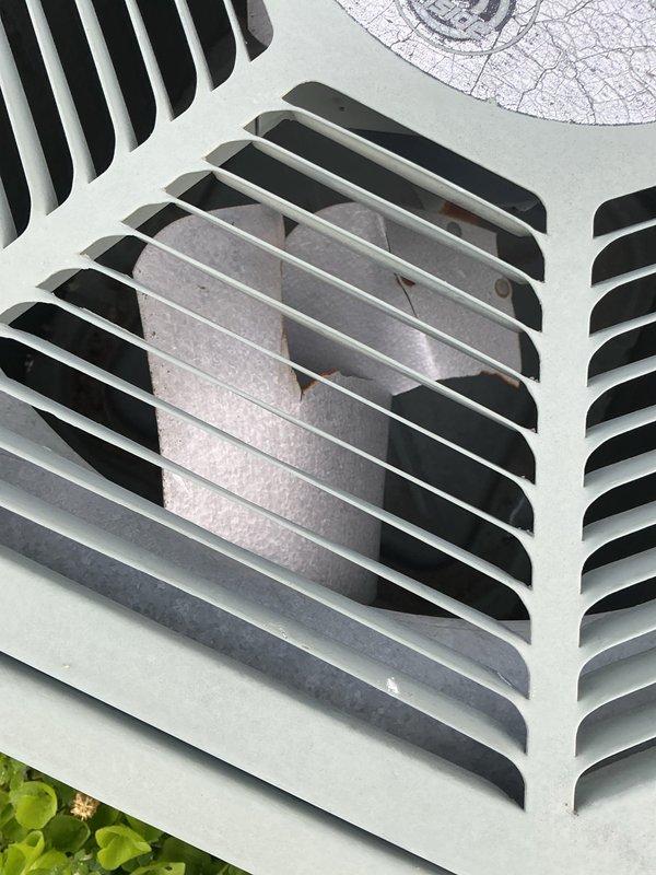 Responded to no-cooling complaint with unit running continuously and unable to maintain temperature setpoint, reaching only 80°F despite thermostat set to 69°F. Upon arrival, performed visual inspection of ground-level condensing unit located in garage area. Documented exterior condition of equipment showing mint green painted cabinet with intact louvered panels and ventilation grilles in satisfactory condition, with foam insulation visible through openings and no apparent physical damage or deterioration to housing components.