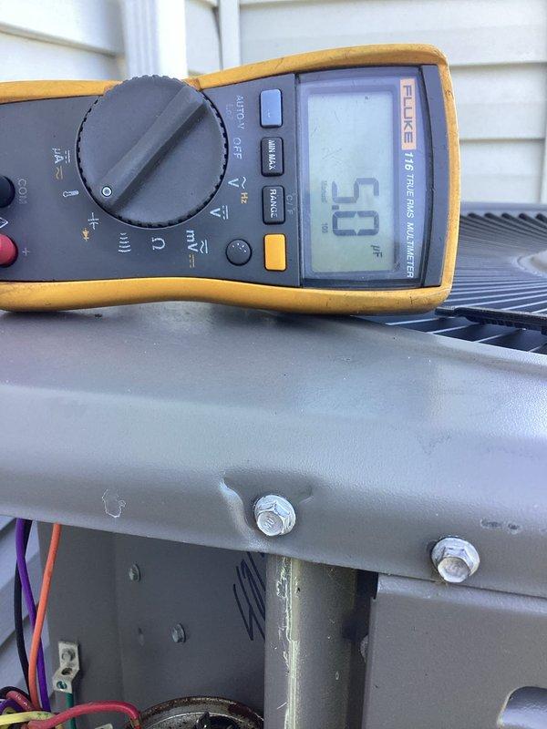 Responded to service call for AC unit making unusual noise and not cooling. Upon arrival, performed diagnostic testing on outdoor condensing unit using digital multimeter to check electrical values and verify proper voltage at terminal connections. Inspected wiring connections at terminal block and verified all electrical connections were secure and within specifications, with unit reading 53 on meter display indicating proper line voltage present at equipment.