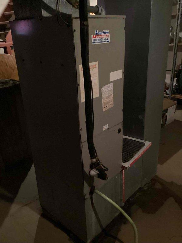 Responded to service call for older residential A/C system with reported refrigerant leak causing insufficient cooling. Upon arrival, inspected outdoor condenser unit (cylindrical style, 10+ years old) located in backyard on concrete pad and indoor Janitrol High Efficiency Plus air handler unit in basement. Performed visual inspection of both components and documented equipment condition with photographs. Confirmed unit operational status and assessed refrigerant system for leak detection. Unit utilizes R-22 refrigerant (Type 3 Freon), which is phased out in newer systems. Noted system age and legacy refrigerant type require specialized service approach for repairs and future maintenance considerations.