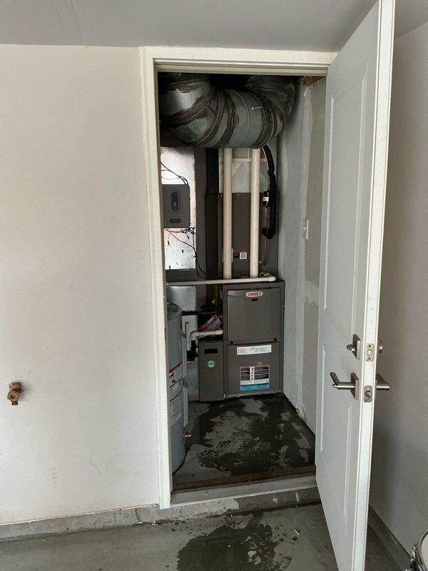Responded to no cooling complaint on residential air conditioning system. Upon arrival, found unit had been shut off. Performed diagnostic evaluation of outdoor condensing unit and indoor air handler system. Inspected electrical connections, refrigerant lines, and control components. Observed water staining on utility room floor near furnace and air handler, indicating potential condensate drainage issue requiring attention. Documented equipment conditions and system layout with photographs for service records.
