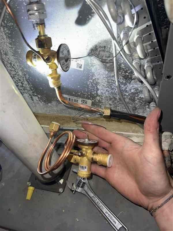 Replaced defective thermal expansion valve (TXV) on system S/N 1522G74733 to restore cooling operation. Unit was experiencing no-cool condition due to failed TXV. Recovered refrigerant, removed old valve assembly, installed new TXV with proper torque specifications on brass fittings, evacuated system, and recharged to manufacturer specifications. Verified proper system operation with temperature differential and pressures within normal range. Retained failed part per protocol.