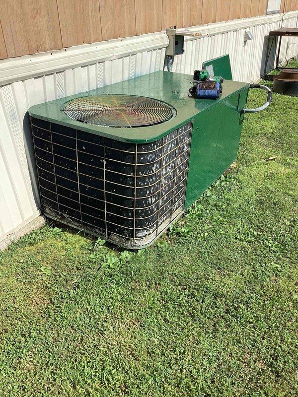 Responded to no cooling complaint on 10+ year old outdoor condensing unit located in backyard. Upon arrival, found system blowing warm air as reported. Performed diagnostic evaluation of aging unit with green-painted top cover and weathered exterior components. Identified issue preventing proper cooling operation and provided customer with repair options and recommendations for restoring system functionality.