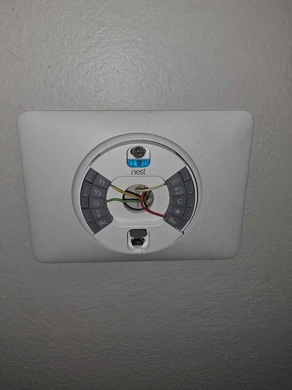 Responded to no cooling call on 1-year-old AC system with Nest thermostat displaying "No power to Rh wire" error. Upon arrival, verified 24V power supply at air handler was functioning properly and all low-voltage wiring connections were secure at both the thermostat and equipment. Inspected condensate drain line and found primary drain clogged, which had triggered the float switch safety shutoff, interrupting power to the Rh terminal. Cleared blockage from condensate line using wet/dry vacuum, flushed drain with water to confirm proper flow, and reset float switch. Restored power to thermostat, verified proper 24V at Rh terminal, and confirmed system returned to normal operation with compressor and air handler cycling correctly.