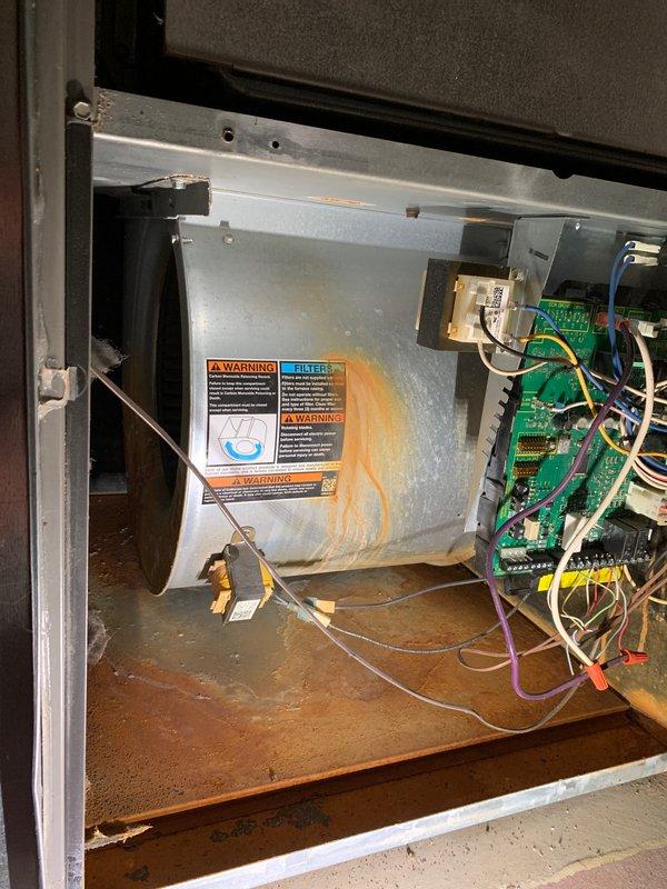 Completed preventive maintenance tune-up on a 10-year-old residential air conditioning system located at side of home. Performed comprehensive inspection of air handler unit in basement, including blower assembly, evaporator coil, electrical connections, and control boards. Verified proper operation of all safety switches and warning labels. Documented existing condition of unit showing age-appropriate wear, minor rust staining on blower housing, and organized wiring to circuit boards. System operational and ready for cooling season.