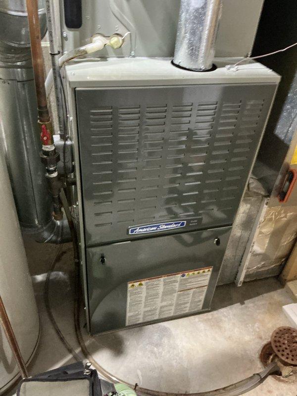 Completed preventive maintenance tune-up on a single American Standard forced-air furnace system approximately 5-10 years old located in basement utility area. Performed comprehensive inspection of furnace cabinet, burner assembly, heat exchanger, and blower components. Checked and documented air filter condition, noting 20x20x1 filters available on-site. Inspected all visible ductwork connections, copper refrigerant lines, shut-off valves, and associated piping for proper operation and secure fittings. Verified system operational status and confirmed unit is functioning properly per manufacturer specifications.