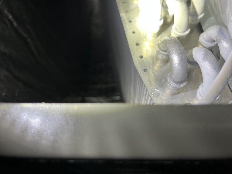 Responded to warranty call for new installation not maintaining proper temperature or dehumidification despite multiple previous service attempts. Upon arrival, discovered severe ice buildup on evaporator coil and refrigerant lines, with large ice formations completely encasing copper piping and connections. Diagnosed restricted airflow and improper refrigerant charge as contributing factors to freezing condition. Allowed system to thaw completely, verified airflow across coil, checked and adjusted refrigerant charge to manufacturer specifications, and confirmed proper operation of all components before departure.