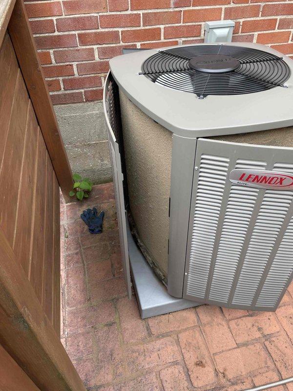 Completed preventative maintenance tune-up on two Lennox air conditioning condenser units located on exterior brick paver patio area. Both units are approximately 10 years old and positioned against red brick wall with wooden privacy fence backdrop. Performed comprehensive seasonal cooling system inspection including refrigerant level verification, electrical component testing, condenser coil cleaning, fan motor operation check, and thermostat calibration on both systems. All equipment operating within manufacturer specifications with no deficiencies noted at time of service.