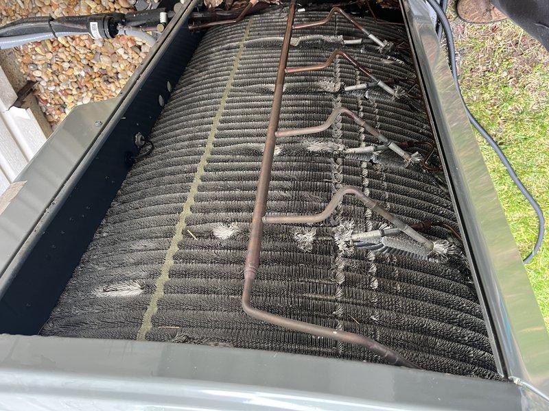 Performed comprehensive cooling system tune-up on single outdoor condensing unit. Upon inspection, found evaporator coil heavily soiled with accumulated debris, dust, and organic matter restricting airflow. Removed top panel to access coil assembly, documented condition with photos, and verified electrical readings using digital multimeter. Cleaned coil fins, removed debris buildup, and inspected refrigerant lines showing normal weathering patina consistent with unit age.