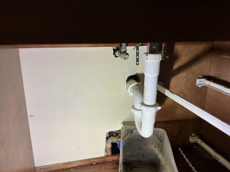 # Bathroom Sink Drain Clearing

Responded to service call for bathroom sink backing up and draining slowly. Upon arrival, accessed cabinet beneath sink and inspected P-trap assembly and drain configuration. White PVC P-trap showed signs of buildup and obstruction causing drainage issues.

Removed P-trap assembly to access blockage. Cleared accumulated debris, hair, soap residue, and sediment from trap and connecting drain lines. Inspected vertical drain pipe for additional obstructions and verified clear flow path through drainage system. 

Cleaned P-trap components thoroughly and reassembled plumbing connections, ensuring proper alignment and secure fittings to prevent future leaks. Tested drain flow by running water through sink to verify complete restoration of drainage function. Confirmed water flows freely without backing up or slow drainage.

Inspected chrome shut-off valves and flexible supply lines during service - all components functioning properly with no leaks detected. Cab