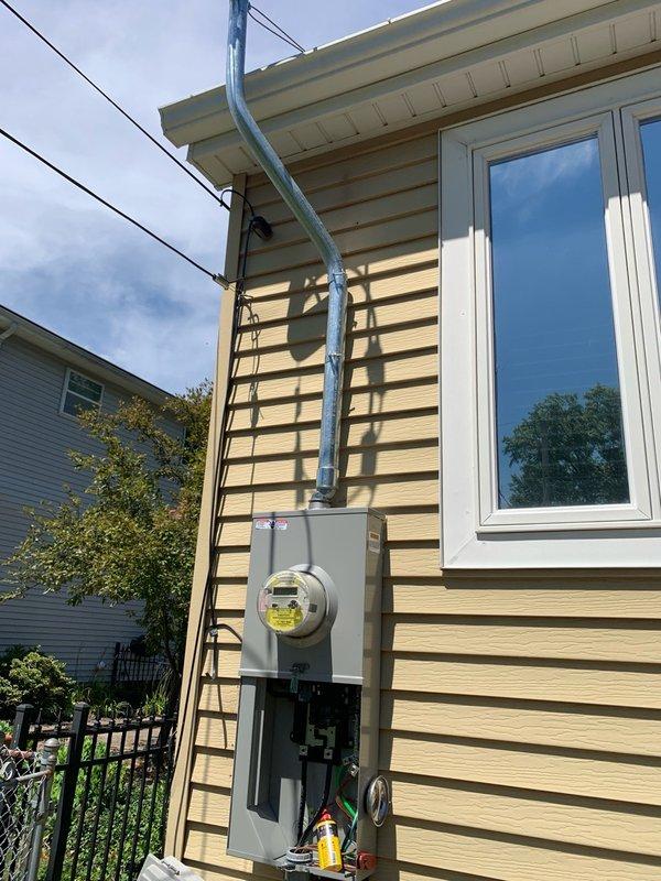 Installed new meter main combination panel on exterior wall of residence with integrated surge protection system. Ran metallic conduit vertically from panel to roofline connection point, securing all components to building siding per code requirements. Completed electrical service upgrade with proper grounding and weatherproof installation.