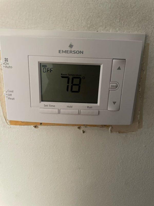 Responded to no cooling complaint on recently installed 2025 unit located in side yard. Upon arrival, found outdoor unit off with only fan running. Verified thermostat operation showing system attempting to cycle but failing to maintain cooling mode. Adjusted thermostat settings from OFF to COOL mode with setpoint at 70°F, confirmed system successfully engaged and began cooling cycle with display indicating "Cool On" at 76°F room temperature. Unit now operating properly and maintaining desired temperature.