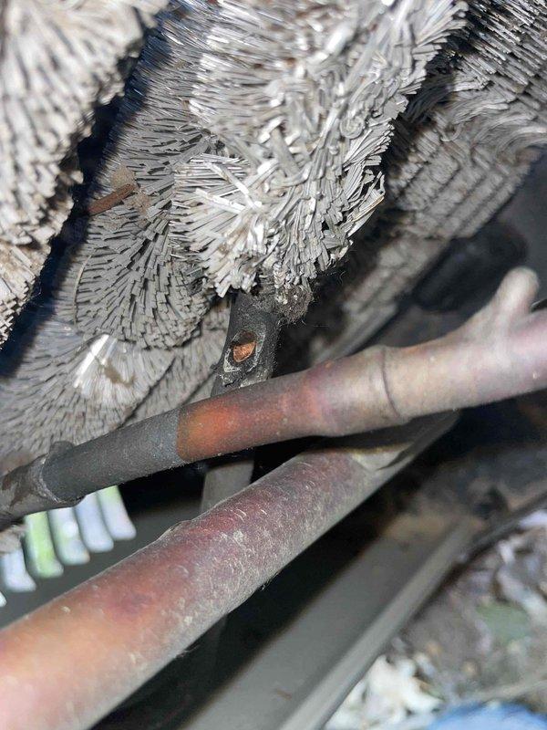 Responded to no cooling complaint on 15-year-old ground-level unit that had received maintenance service days prior. Upon inspection, discovered extensive ice formation on evaporator coil and refrigerant lines, indicating restricted airflow rather than low refrigerant charge. Found evaporator coil heavily contaminated with dust and debris buildup between fins, preventing adequate air circulation across heat exchanger. Documented frozen coil conditions with significant frost crystallization on copper suction line and coil surfaces. System shut down to allow complete ice melt before further diagnosis. Identified restricted airflow as root cause of warm air complaint, requiring coil cleaning and possible blower motor evaluation to restore proper system operation.