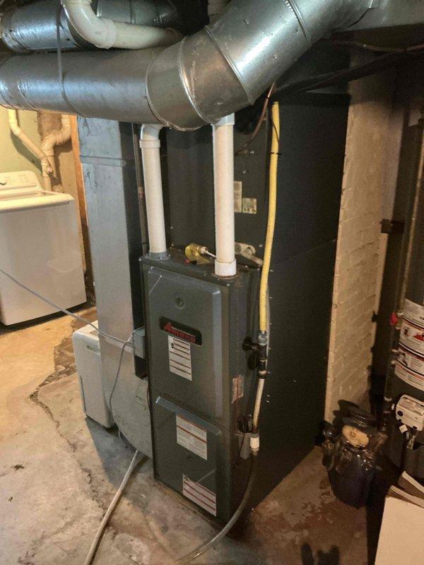 Completed comprehensive air conditioning tune-up on single outdoor unit located at ground level on side of home. Performed standard maintenance protocol including system inspection, filter evaluation, and equipment assessment of furnace and HVAC components in basement mechanical room. All equipment photographed and documented, with air filter showing clean condition and proper wire grid support structure intact, and furnace unit with connected ductwork and PVC venting operating within normal parameters.