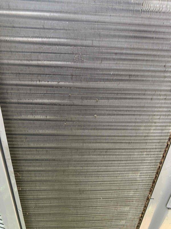 Completed comprehensive tune-up service on single residential air conditioning unit located at ground level. Performed standard maintenance protocol including inspection of evaporator coil assembly, which showed typical dust and dirt accumulation on fin surfaces. Documented equipment condition through photographic records showing corrugated metal fins with operational wear patterns consistent with normal system usage.