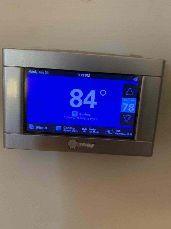 Responded to no-cooling complaint on single HVAC system. Upon arrival, found Trane thermostat displaying 84°F actual temperature while set to 78°F cooling mode, indicating system was not maintaining setpoint. Verified thermostat had power and was properly configured in cooling mode with scheduled programming active. Inspected Lennox furnace/air handler unit located in basement utility area and confirmed proper installation and accessibility. Troubleshot thermostat communication and system operation to restore cooling functionality.
