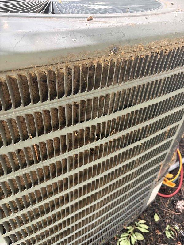 # Service Summary

Responded to no cooling complaint on 25-year-old ground-level AC unit. Upon arrival, found outdoor condenser with heavily clogged coil fins restricting airflow, preventing proper heat exchange and causing warm air discharge indoors.

# Work Performed

Performed diagnostic evaluation of condenser unit experiencing no cooling condition. Visual inspection revealed significant dirt, dust, and debris accumulation throughout heat exchanger coil fins, severely impacting system performance. The condenser showed signs of extended operation without routine maintenance, with environmental contamination blocking adequate airflow through the coil assembly.

Documented unit condition through photography showing extent of debris buildup on cooling fins and overall weathered state of 25-year-old equipment. Prior to service arrival, instructed occupant to power off AC unit while maintaining fan operation to prevent compressor damage and provide air circulation.

Assessed secondary co