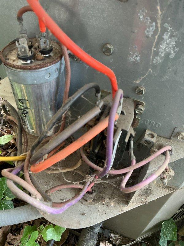 # HVAC Service Completed

Responded to no-cooling complaint on residential air conditioning system over 10 years old located at side of home. Upon arrival, found unit had been shut off by customer. Performed diagnostic evaluation of outdoor condensing unit and discovered severely corroded capacitor with rust damage at terminal connections. Capacitor showed signs of extended weather exposure and component failure, which prevented compressor from starting and caused complete loss of cooling function.

Documented deteriorated electrical components including weathered wiring connections and corroded capacitor housing. Unit's exterior panel exhibited significant wear with peeling paint and corrosion, consistent with age and outdoor environmental exposure. Vegetation growth near unit base indicated potential airflow restriction concerns.

Inspected indoor air handler and furnace unit in basement to verify system integrity. Noted dust accumulation and signs of aging throughout equipment. Duct
