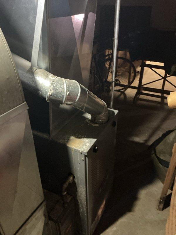 # HVAC Service Completed

Responded to no-cooling complaint on residential air conditioning system over 10 years old located at side of home. Upon arrival, found unit had been shut off by customer. Performed diagnostic evaluation of outdoor condensing unit and discovered severely corroded capacitor with rust damage at terminal connections. Capacitor showed signs of extended weather exposure and component failure, which prevented compressor from starting and caused complete loss of cooling function.

Documented deteriorated electrical components including weathered wiring connections and corroded capacitor housing. Unit's exterior panel exhibited significant wear with peeling paint and corrosion, consistent with age and outdoor environmental exposure. Vegetation growth near unit base indicated potential airflow restriction concerns.

Inspected indoor air handler and furnace unit in basement to verify system integrity. Noted dust accumulation and signs of aging throughout equipment. Duct