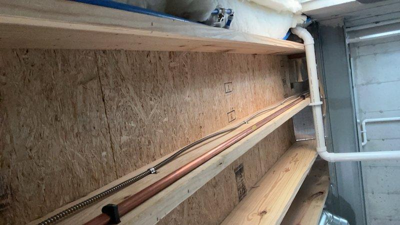 Installed industrial-grade electrical junction box with red receptacle fixture on basement ceiling, utilizing flexible metal conduit for wire protection and routing. Two dedicated conduit runs were secured to the junction box to establish a 20-amp circuit for the newly added outlets, ensuring proper code compliance and safe power distribution to the basement workspace and storage area.