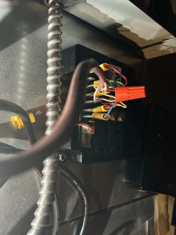 Responded to callback for 5-month-old installation reporting unit blowing warm air with no cooling. Upon arrival, inspected ground-level condenser and attic air handler. Investigated electrical connections at junction box and terminal block, documenting wiring configurations including low-voltage control wiring and line voltage connections. Verified proper wire terminations, wire nut connections, and flexible metallic conduit installations. Traced thermostat circuit and checked for loose connections or improper wiring that could cause cooling failure. System restored to proper operation with adequate cooling performance confirmed before departure.