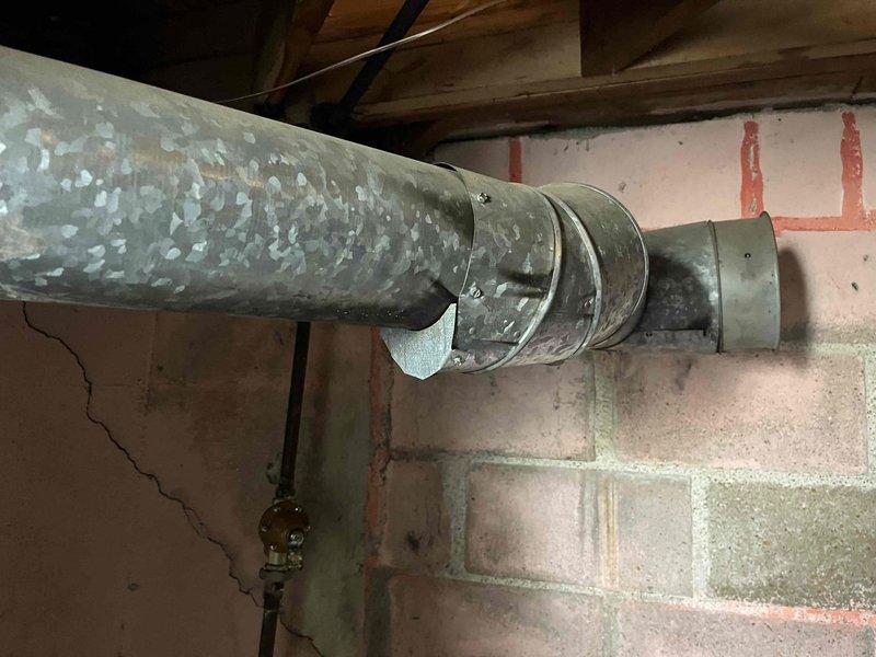Responded to no cooling call on 8-year-old ground-level unit in basement. Upon arrival, found system running continuously with blower operating but no cooling output. Performed diagnostic evaluation of HVAC system and inspected accessible components including ductwork, which showed significant age-related deterioration with peeling insulation coating and wear at connection points. Documented system conditions with photographs showing weathered ductwork with exposed metal sections and compromised connections near wall penetrations. Verified customer had turned off cooling and humidifier fan operation as requested prior to service visit. Assessed unit's mechanical systems and identified cooling failure requiring further diagnosis to determine specific component malfunction preventing refrigeration cycle operation.